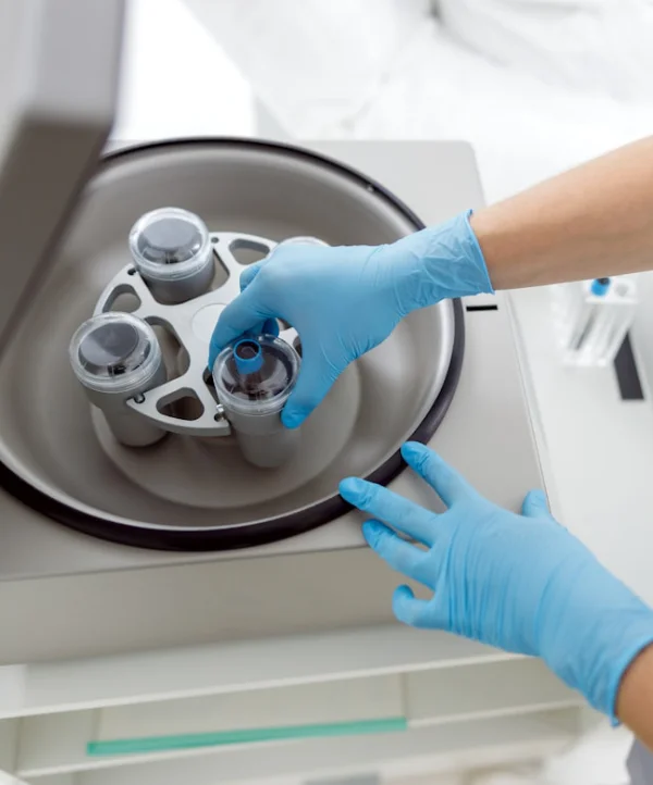 A practitioner placing extracted blood into a centrifuge